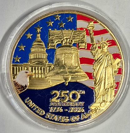 A 250th Anniversary United States of America commemorative coin in a clear protective plastic capsule, featuring gold-toned details of the Capitol dome, Liberty Bell, Statue of Liberty, and an eagle, with a blue and red American flag background.
